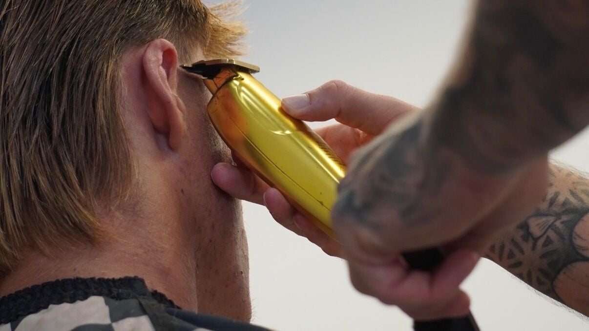 Close up of a gold trimmer cleaning up around the ear